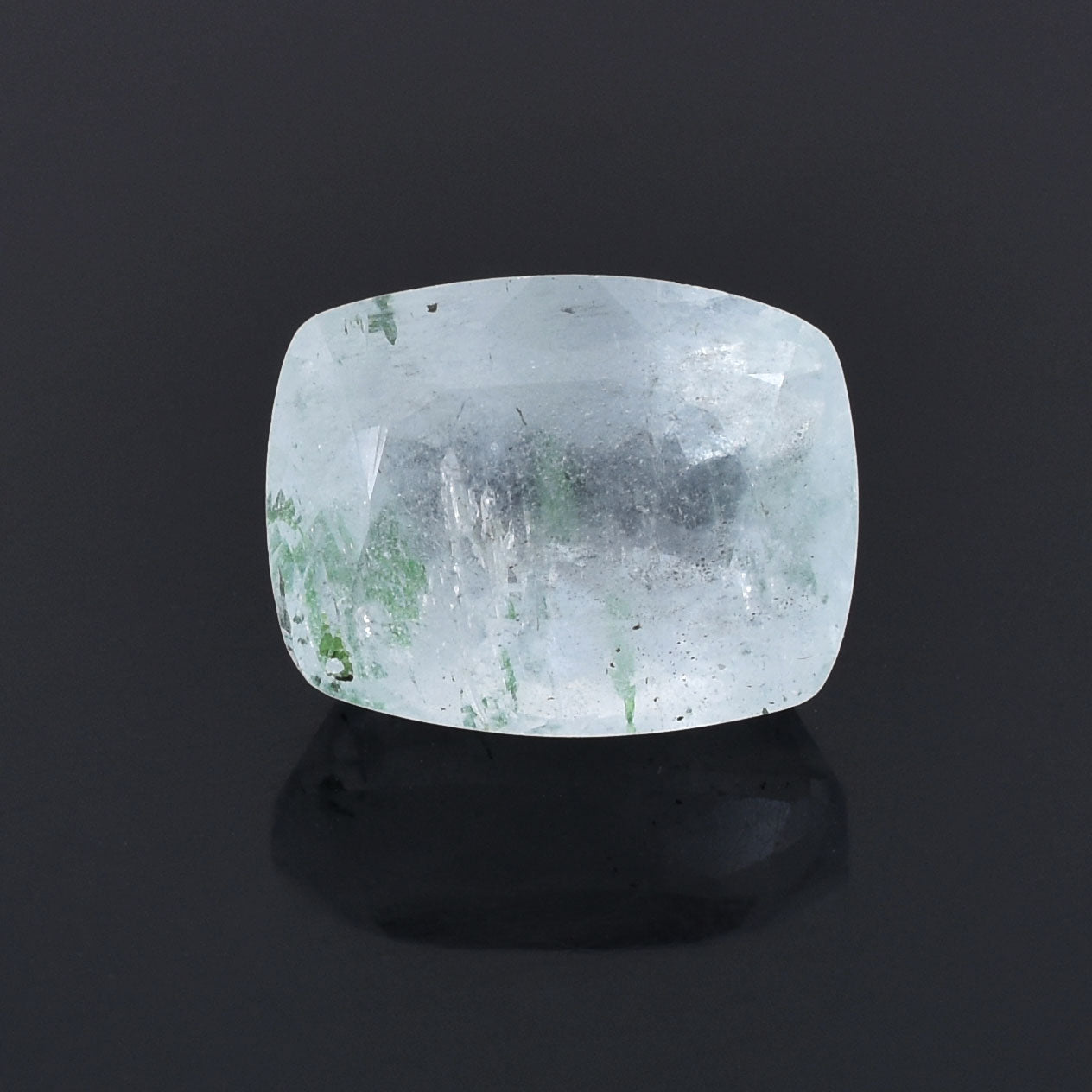Translucent cushion-cut gemstone with green inclusions.