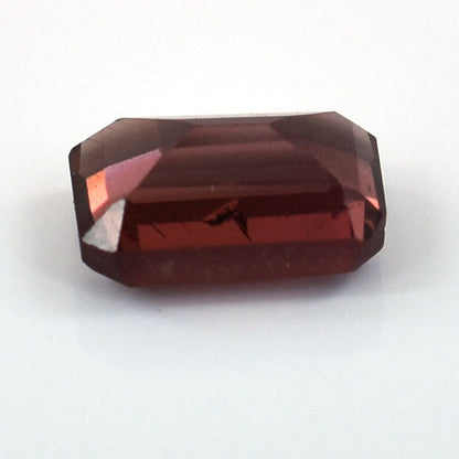 Faceted deep red gemstone with a rectangular emerald cut shape.