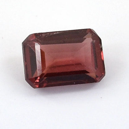 Rectangular-cut deep red gemstone with faceted edges.