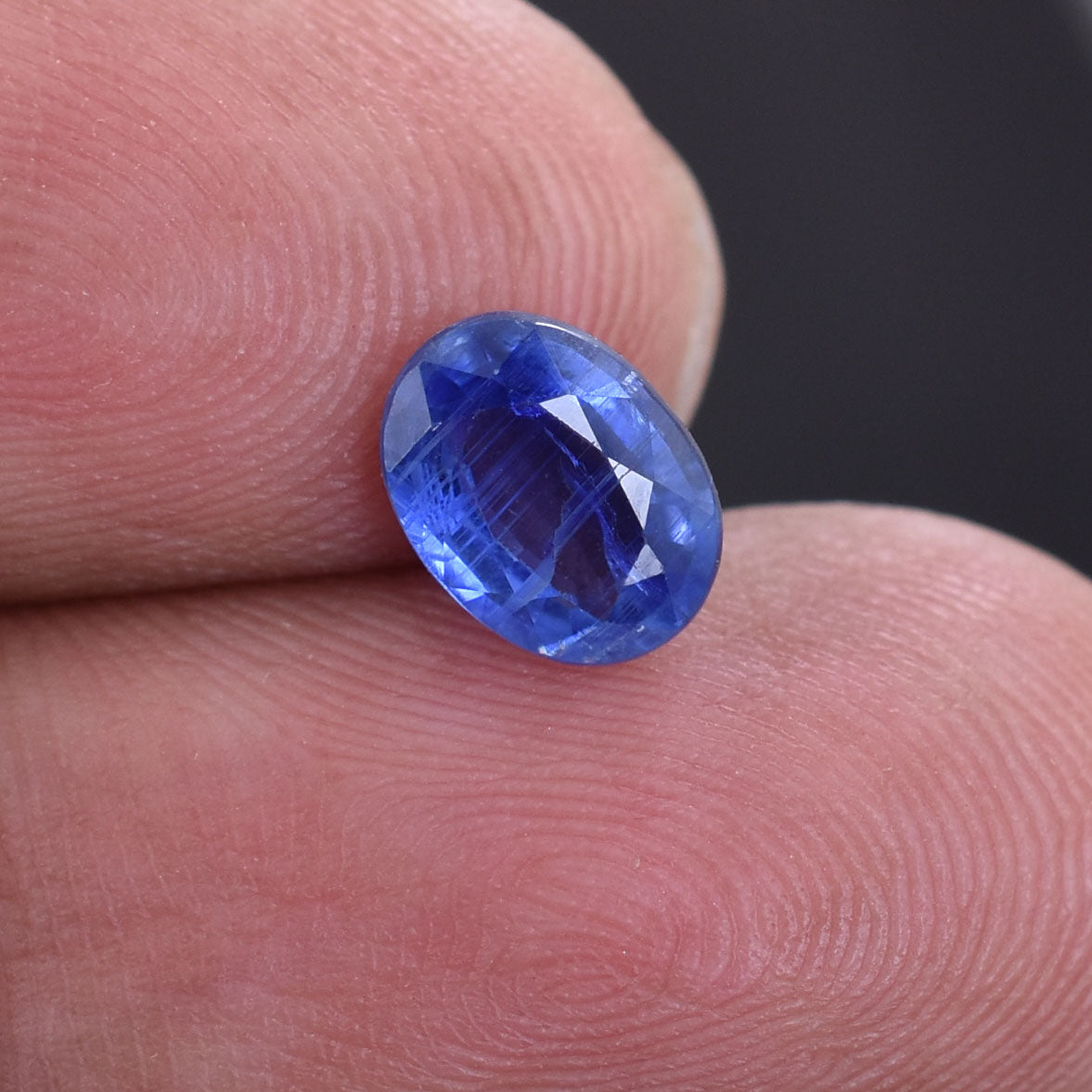 Brilliant blue oval-cut gemstone, likely a sapphire.