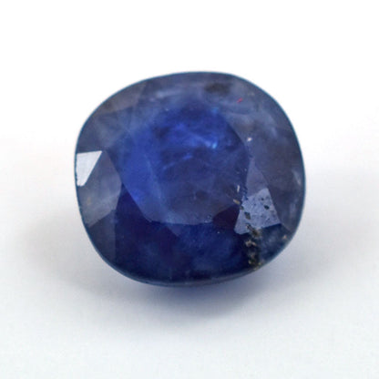 Deep blue faceted sapphire gemstone with a cushion cut shape.