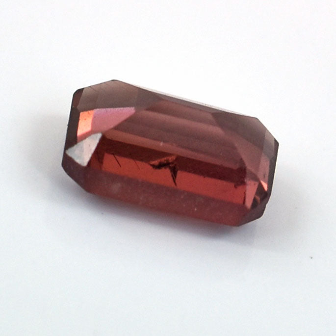 Faceted red gemstone with an emerald-cut shape.