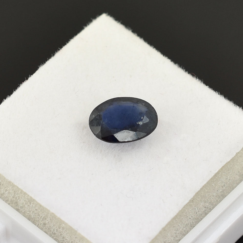 Oval-shaped dark blue gemstone, likely a sapphire.