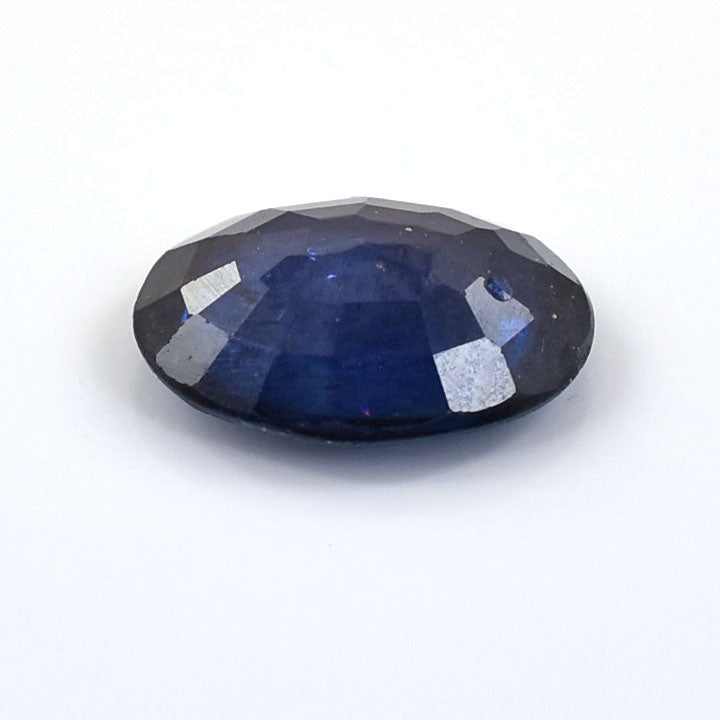 Oval-cut deep blue gemstone with faceted surfaces.