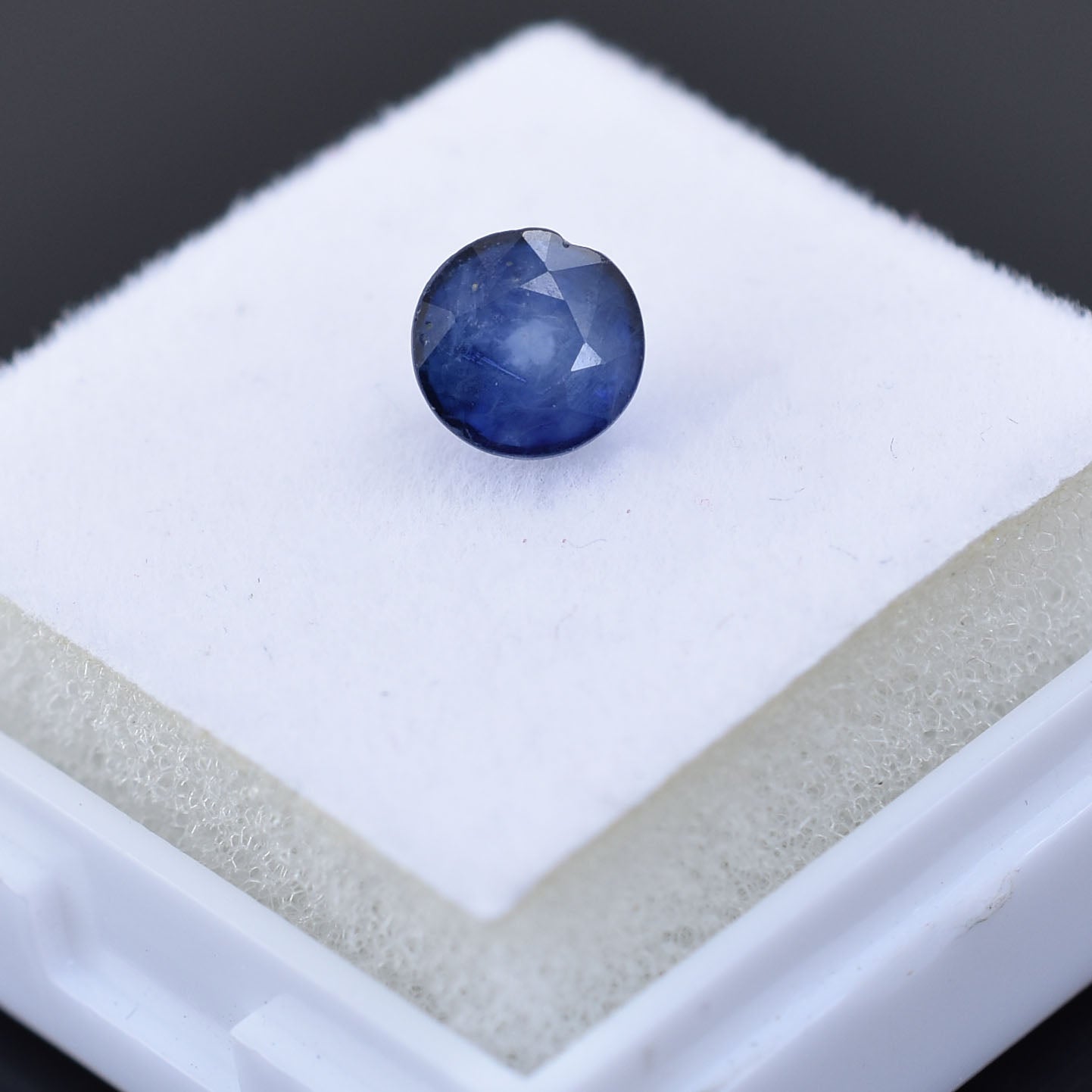 Round blue gemstone with a faceted surface.