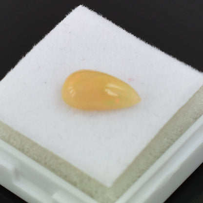 Teardrop-shaped yellow gemstone on a white surface.