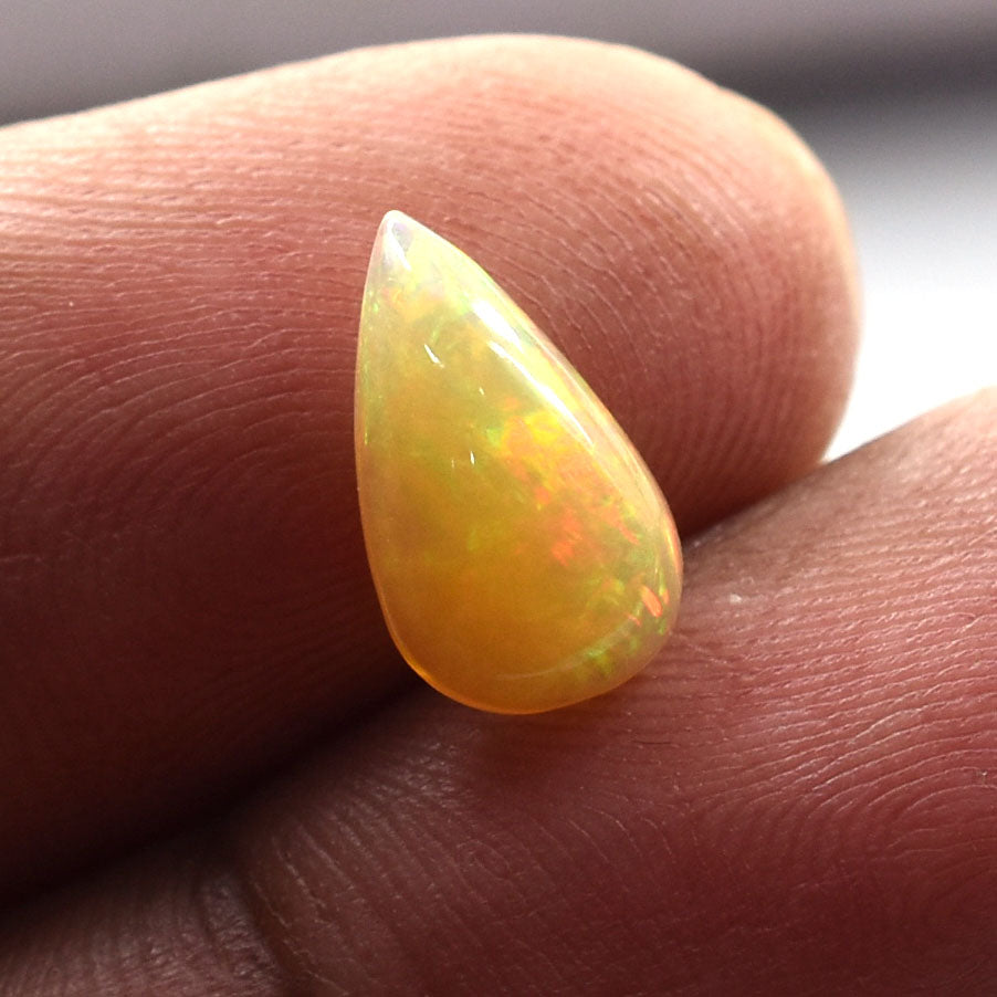 Teardrop-shaped opal gemstone with yellow-orange coloration and iridescent flashes.