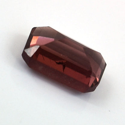 Faceted deep red gemstone with a rectangular shape.