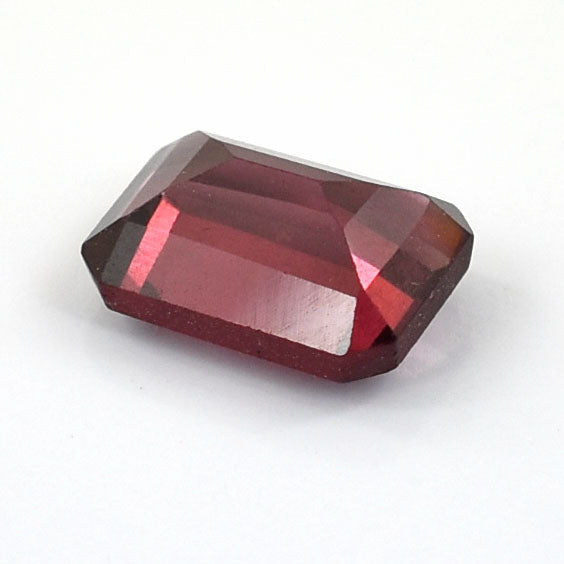 Faceted red gemstone with an emerald-cut shape.