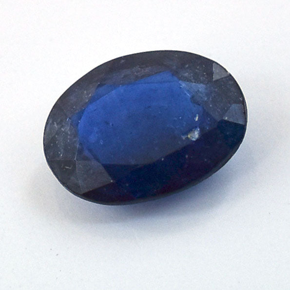 Deep blue oval-cut gemstone, likely a sapphire.