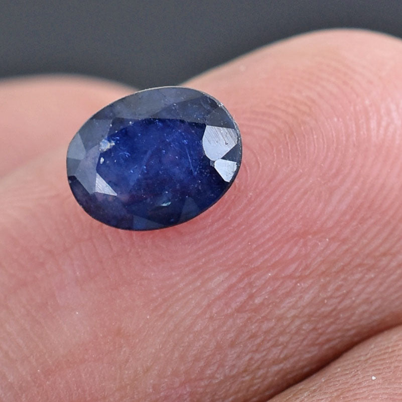 Deep blue oval-cut gemstone, likely a sapphire.