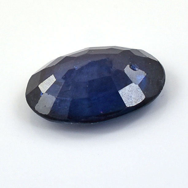 Oval-cut deep blue gemstone with faceted surfaces.