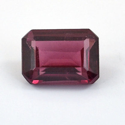 Emerald-cut purple gemstone with a deep reddish hue.