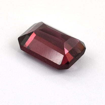 Faceted deep red gemstone with a rectangular emerald cut shape.