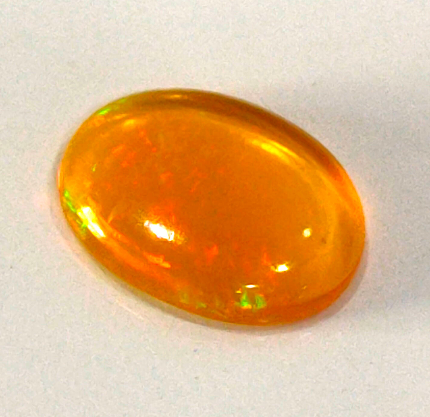 Oval-shaped, translucent orange gemstone or crystal with a smooth, polished surface.