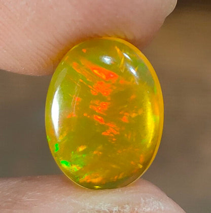 Oval-shaped opal gemstone with vibrant yellow-orange coloration and fiery internal flashes.