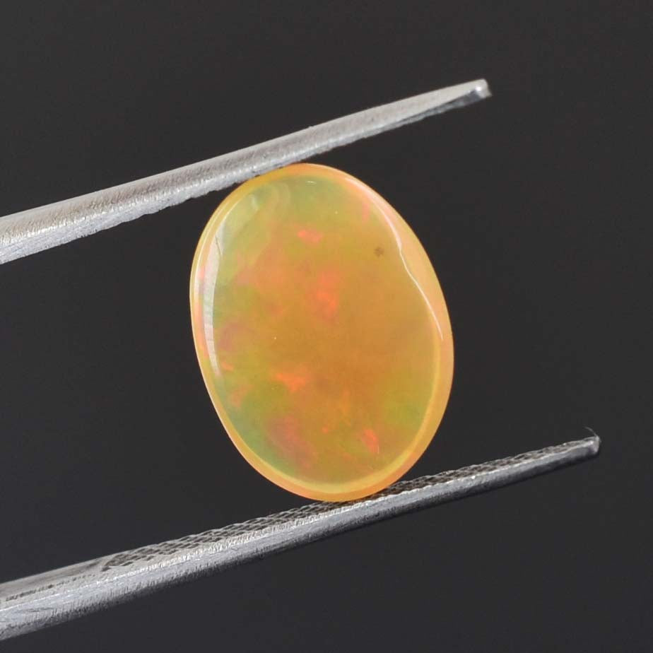 Oval-shaped opal gemstone held between tweezers.