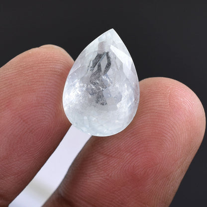 Teardrop-shaped clear crystal or gemstone held on a white stick.