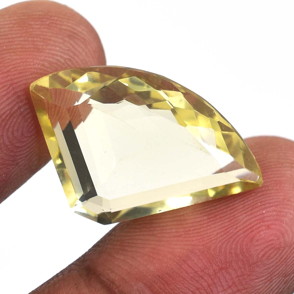 Faceted yellow gemstone held between two fingers.