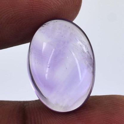 Oval-shaped lavender gemstone or cabochon held between fingers.