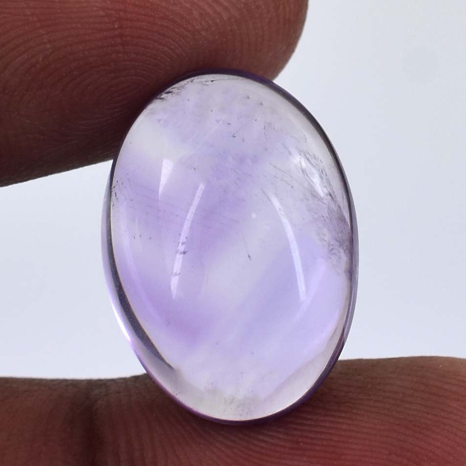 Oval-shaped lavender gemstone or cabochon held between fingers.