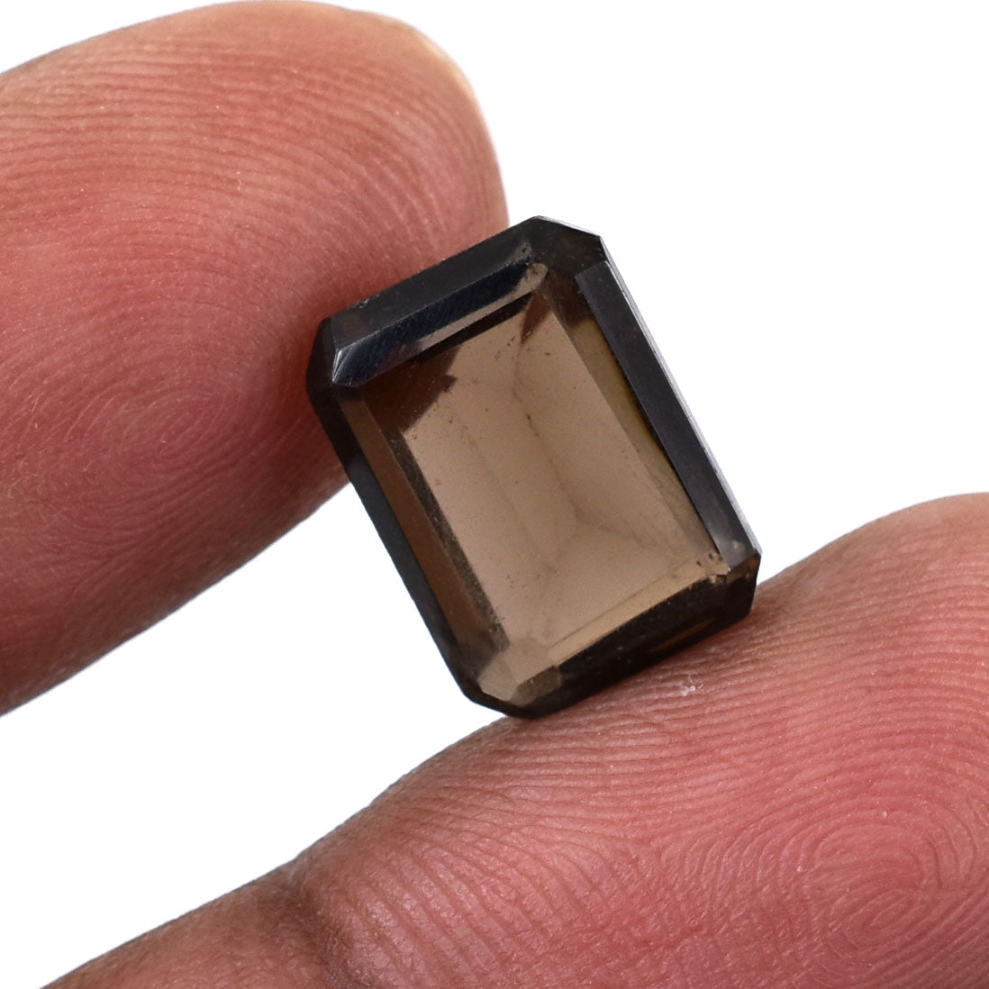 Rectangular-cut smoky quartz gemstone held between two fingers.