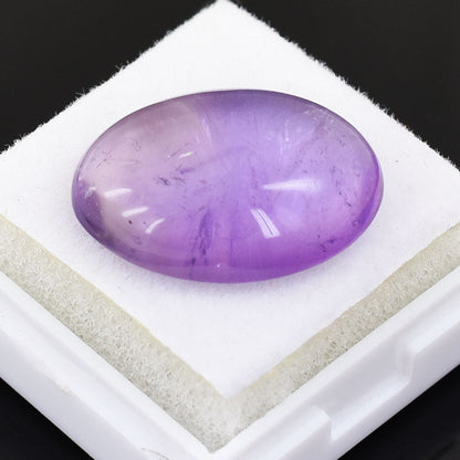 Polished oval amethyst gemstone with a smooth cabochon cut.