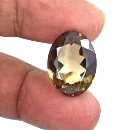 Oval-cut smoky quartz gemstone held between fingers.