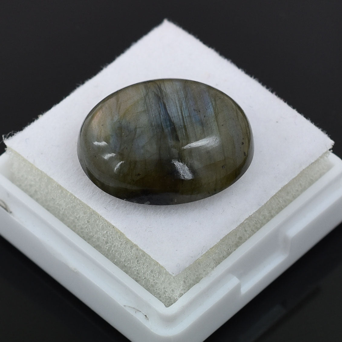 Oval-shaped labradorite gemstone with dark green iridescent coloring.