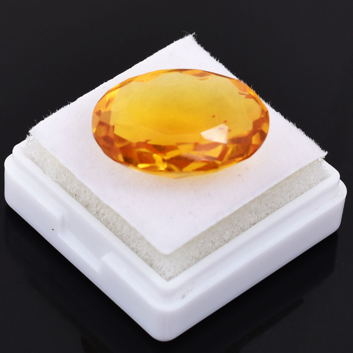 Oval-cut amber or citrine gemstone on a white display stand.