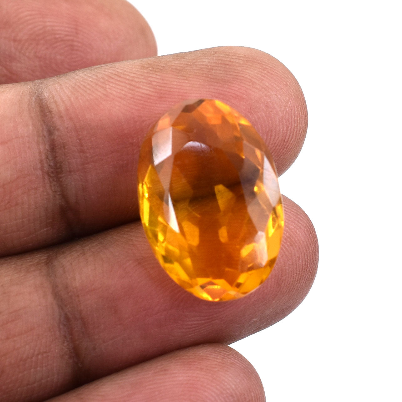 Oval-cut, faceted orange gemstone held between fingers.