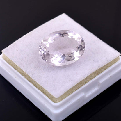 Oval-cut clear gemstone, likely a diamond or crystal, on a white display pad.