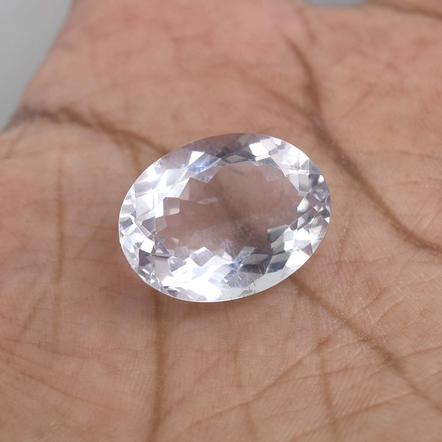 Oval-cut, clear gemstone with facets reflecting light.