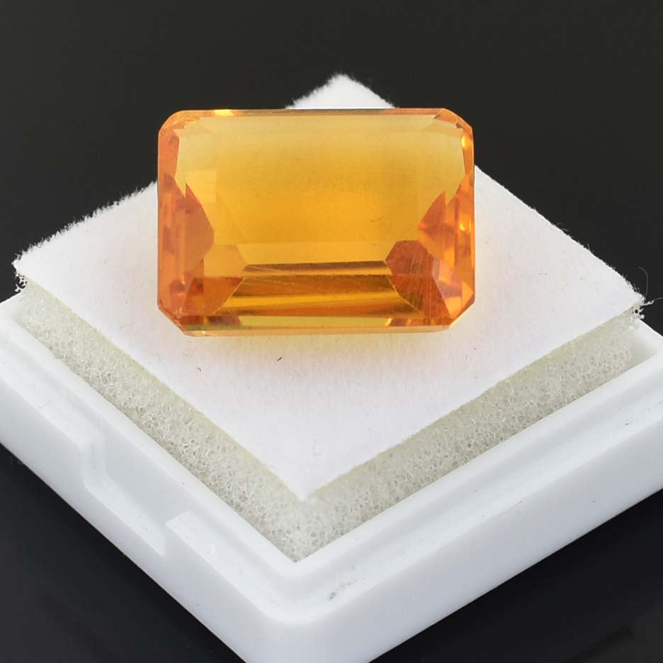 Rectangular-cut orange gemstone or crystal on a white display stand.