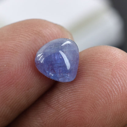 Smooth, rounded blue gemstone resting on a fingertip.