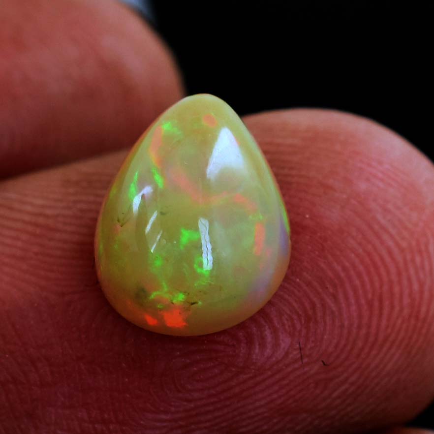 Teardrop-shaped opal gemstone with vibrant green and orange flashes.