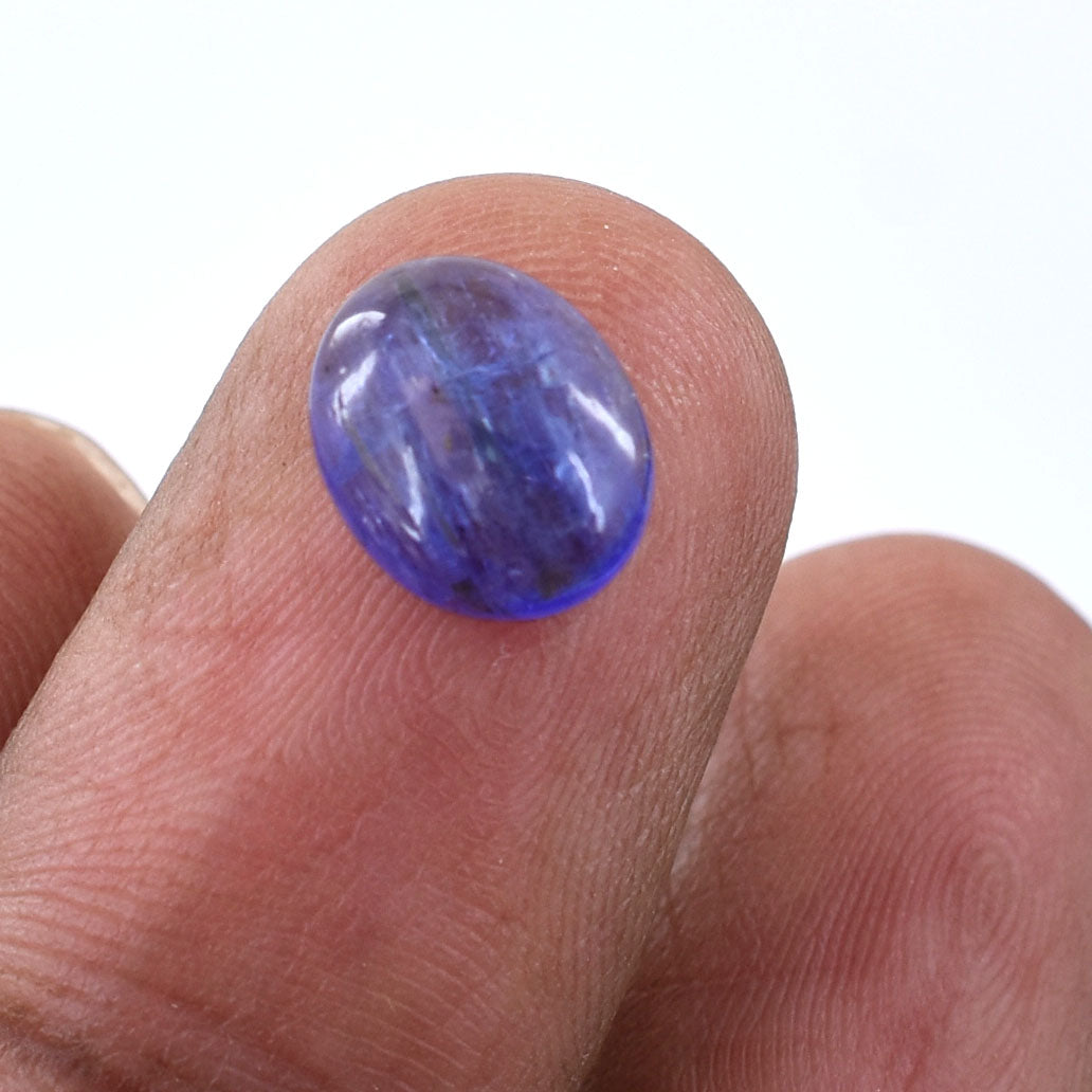 Oval-shaped blue gemstone held on a fingertip.