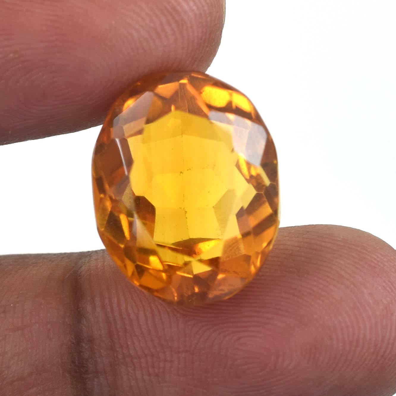 Faceted orange-yellow gemstone held between two fingers.