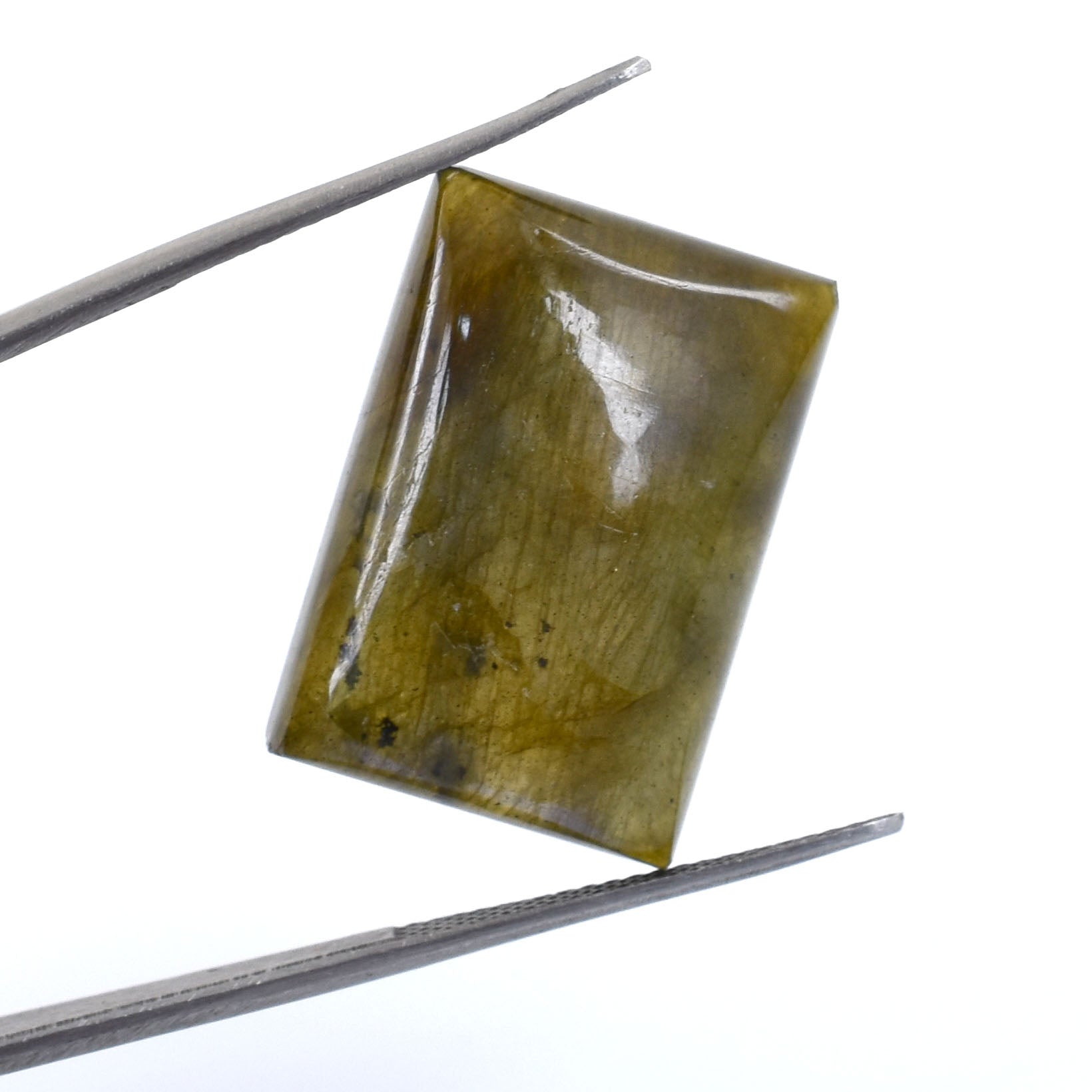 Rectangular, translucent yellow-green gemstone held between metal tweezers.