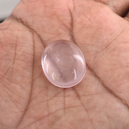 Translucent pink spherical gemstone or crystal resting in a palm.