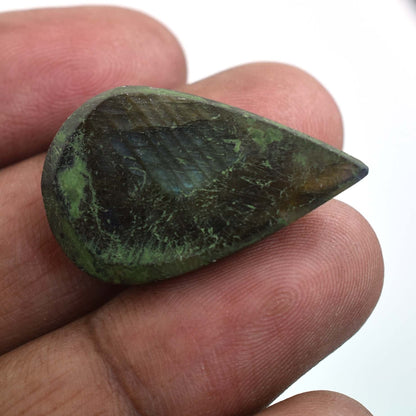 Teardrop-shaped green gemstone or mineral held between fingers.