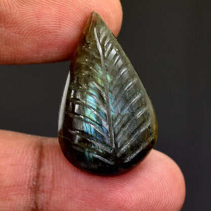 Teardrop-shaped gemstone carved with a feather-like pattern displaying iridescent blue-green colors.