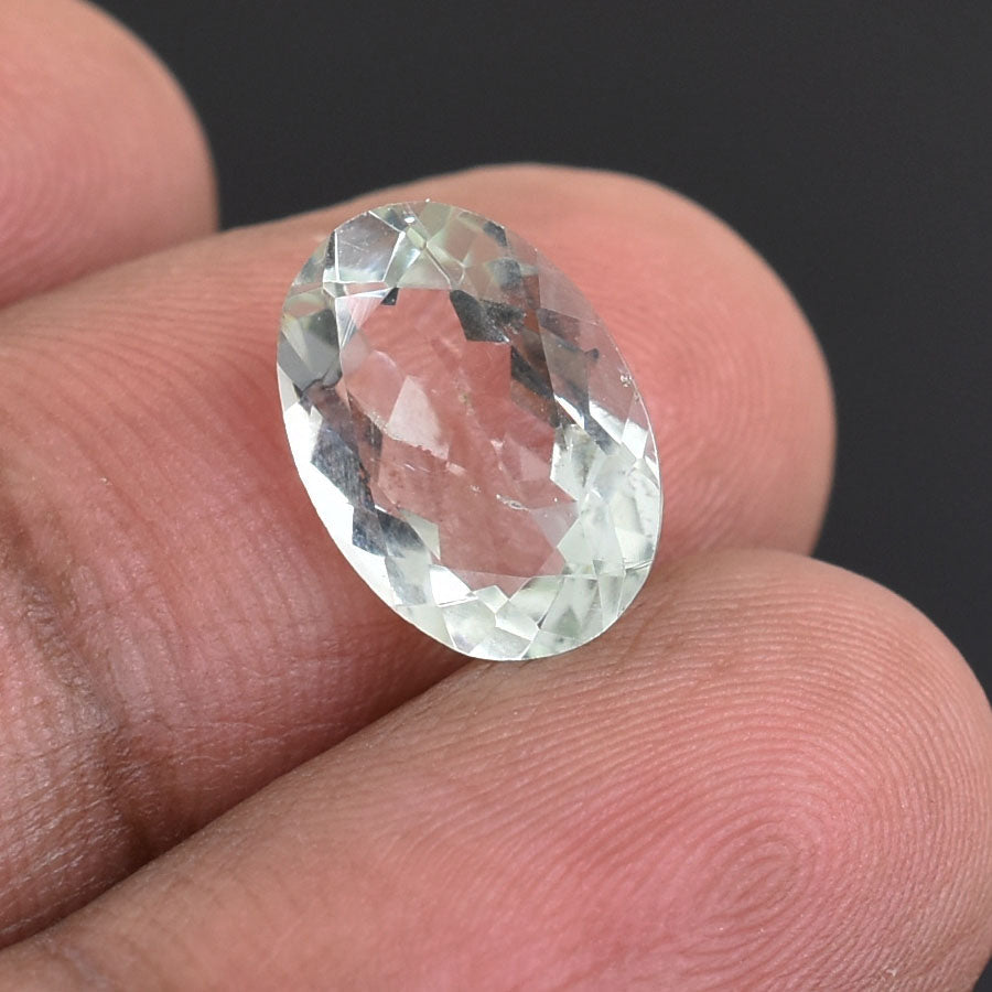 Oval-cut, clear gemstone held between fingers.