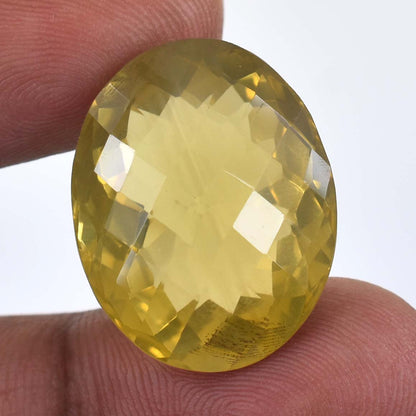 Faceted oval yellow gemstone held between two fingers.