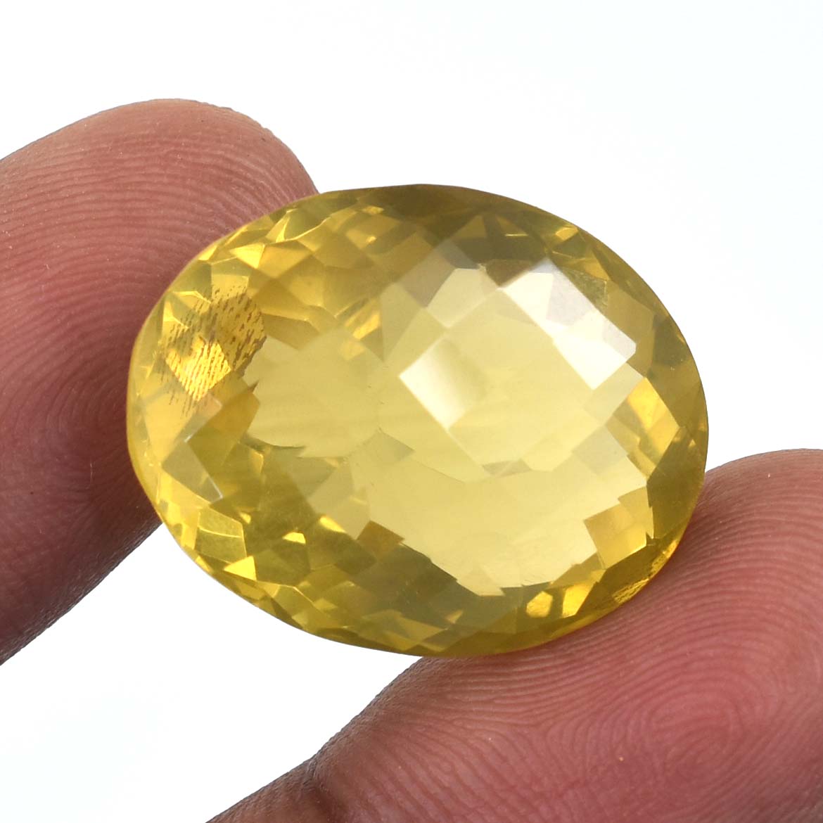 Faceted oval yellow gemstone held between two fingers.