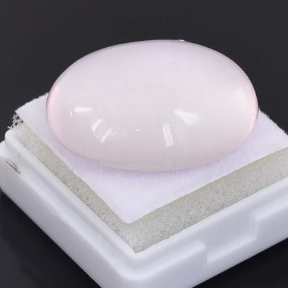 Smooth, pale pink oval gemstone or cabochon on a white display stand.