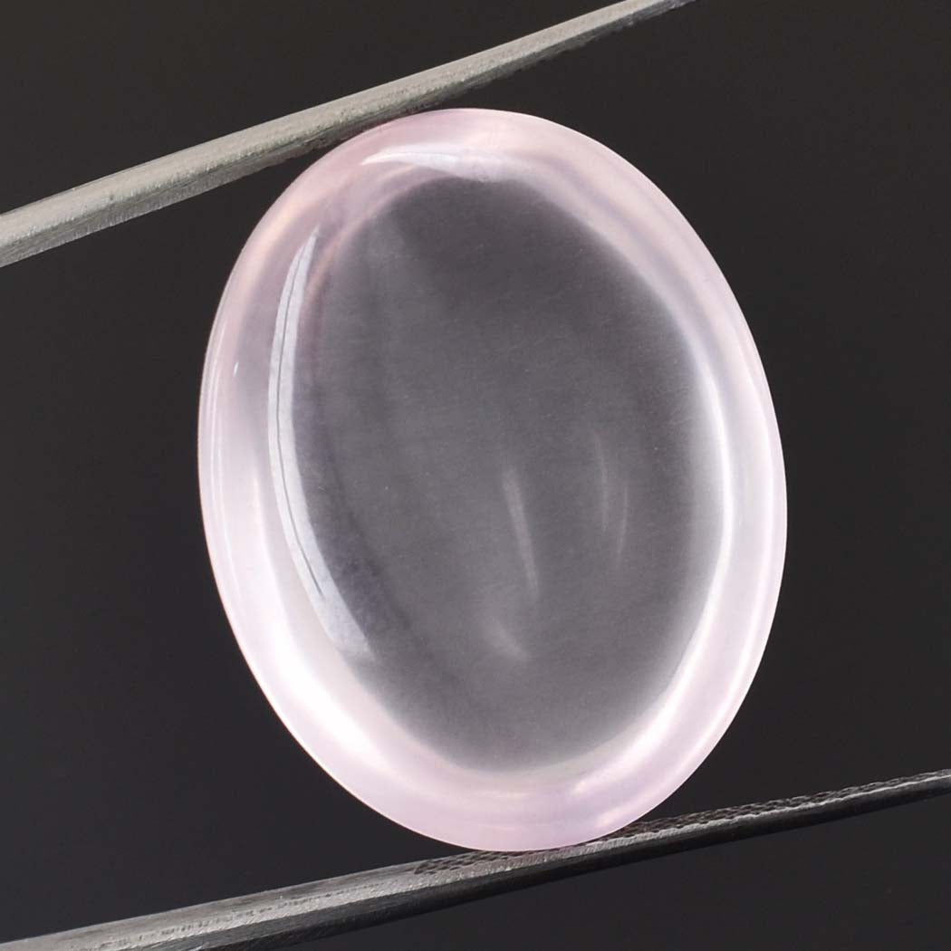 Oval-shaped, translucent pink gemstone or cabochon held by tweezers.