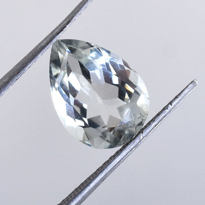 Pear-shaped diamond or gemstone held by tweezers.