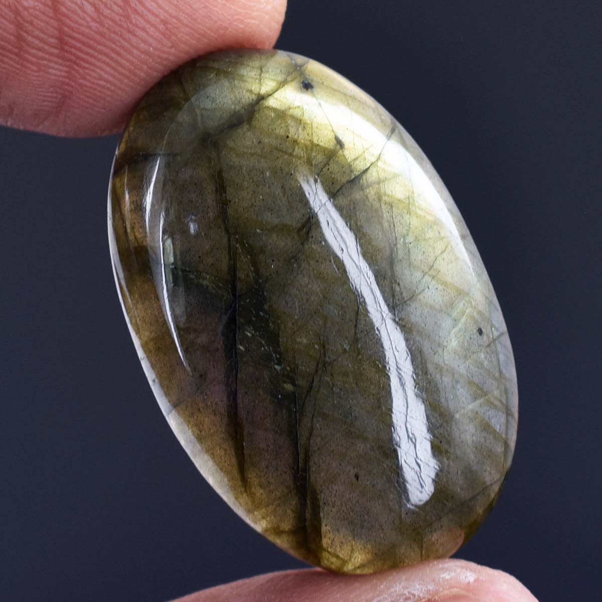 Smooth, oval-shaped gemstone with greenish-yellow hues and dark inclusions.