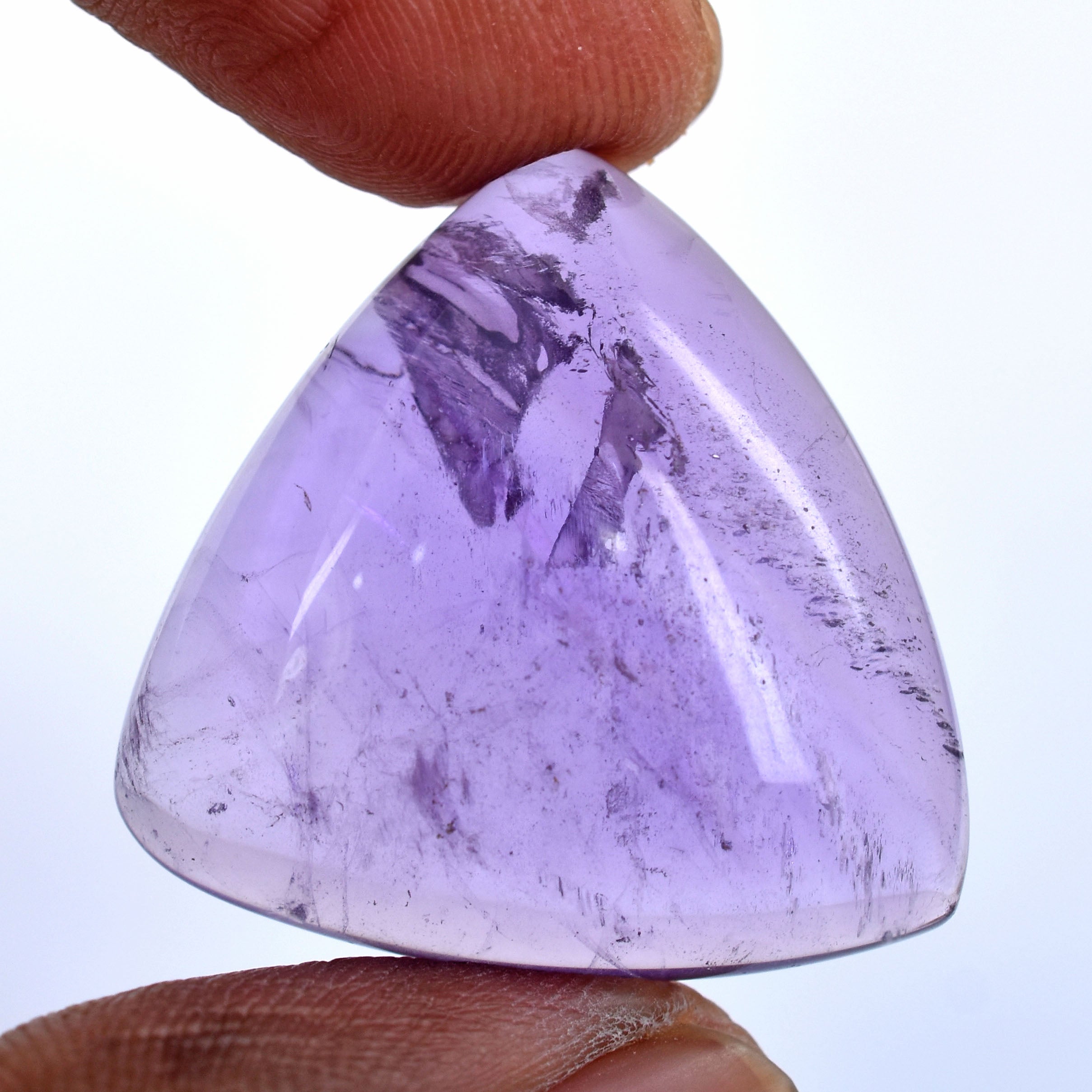 Triangular purple gemstone or crystal held between fingers.